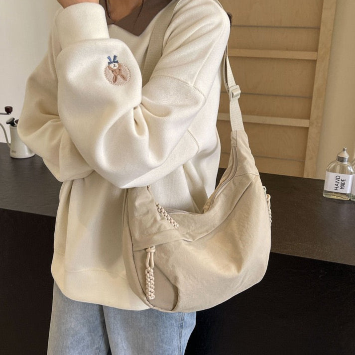 Model wearing STOKADO off-white nylon student shoulder bag